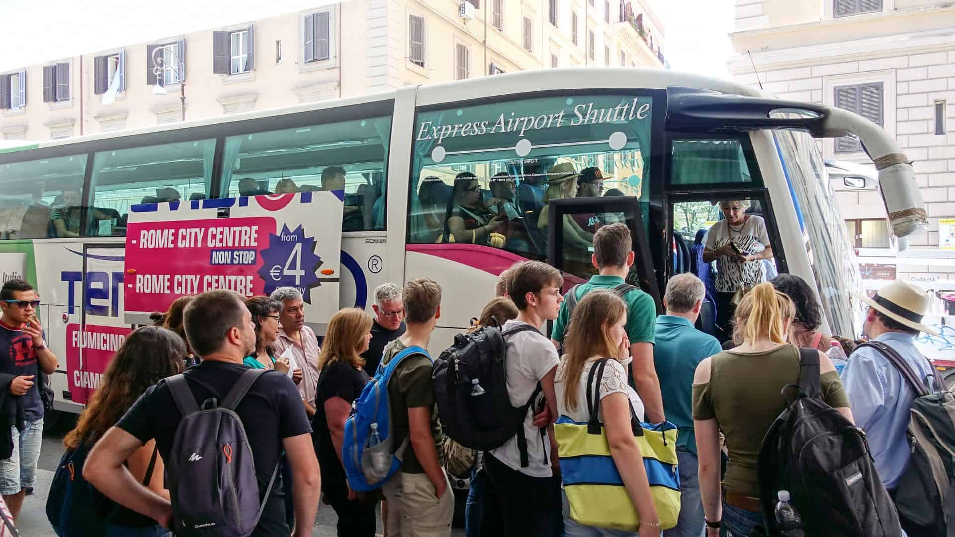 A group of people wait to board an airport shuttle bus.