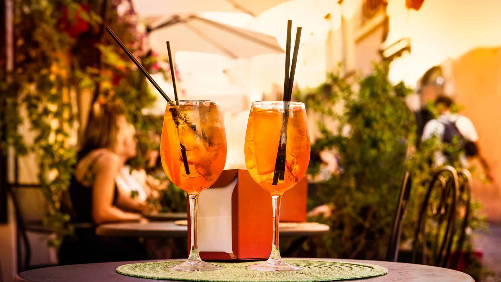 Two aperol spritzs sit on a table in Rome.