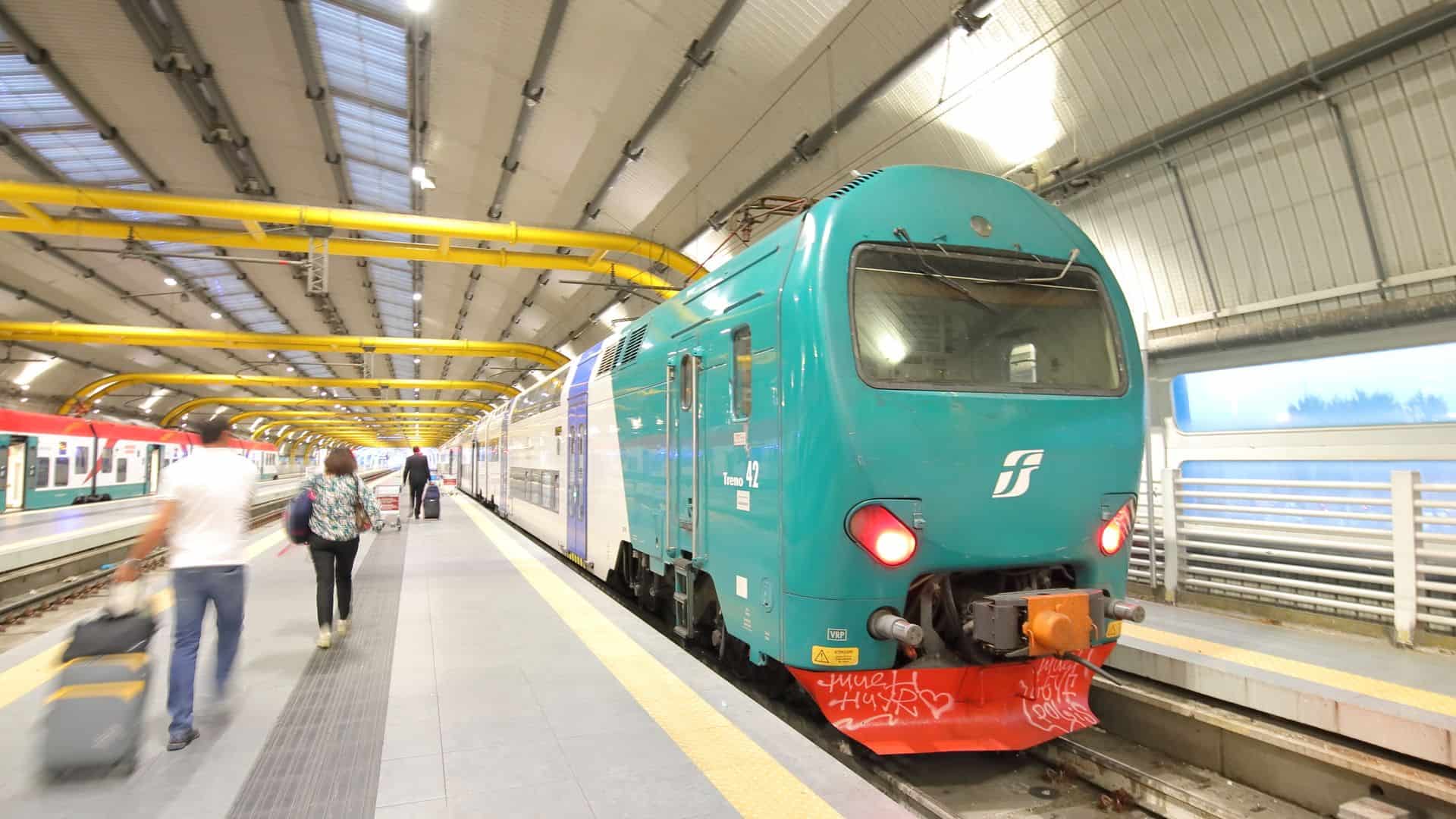 People walking to a train inside the Fiumicino Airport train station.