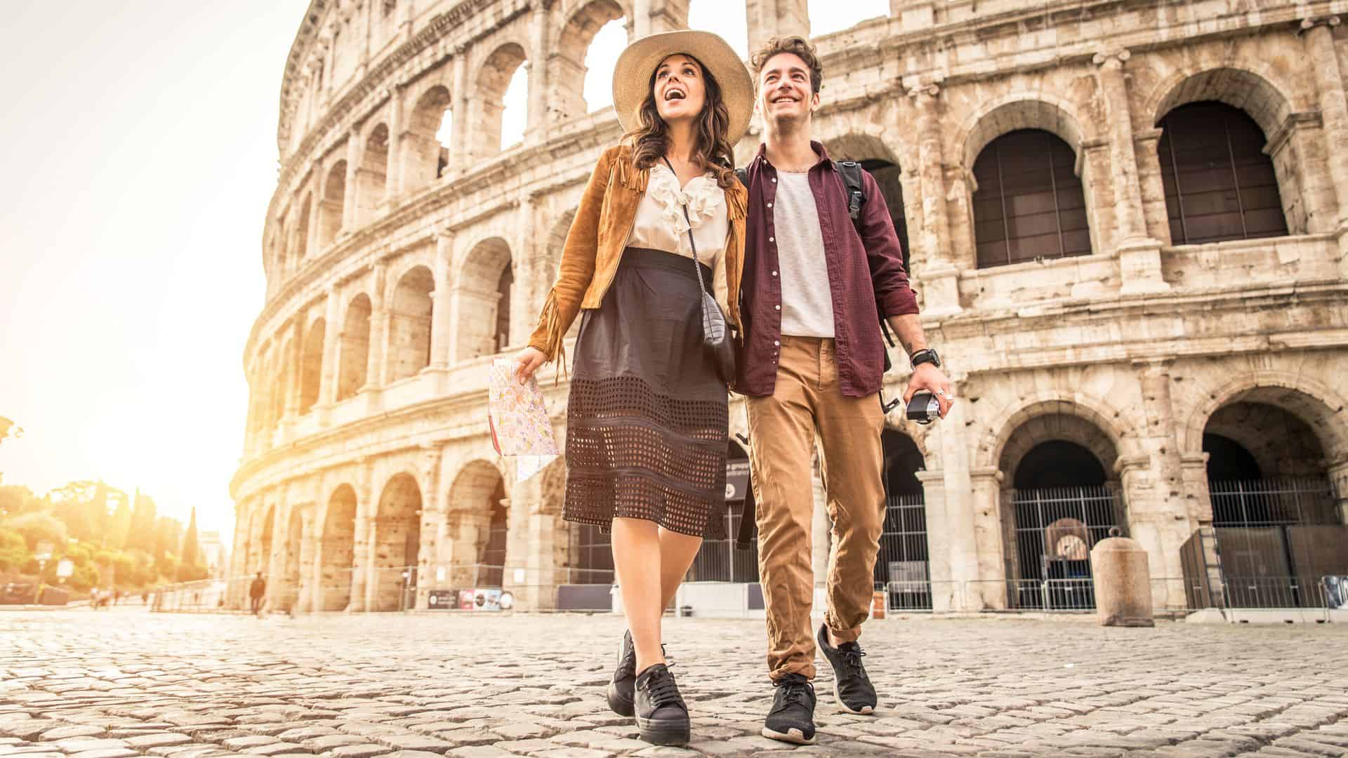 A happy couple walk in front of the Colosseum