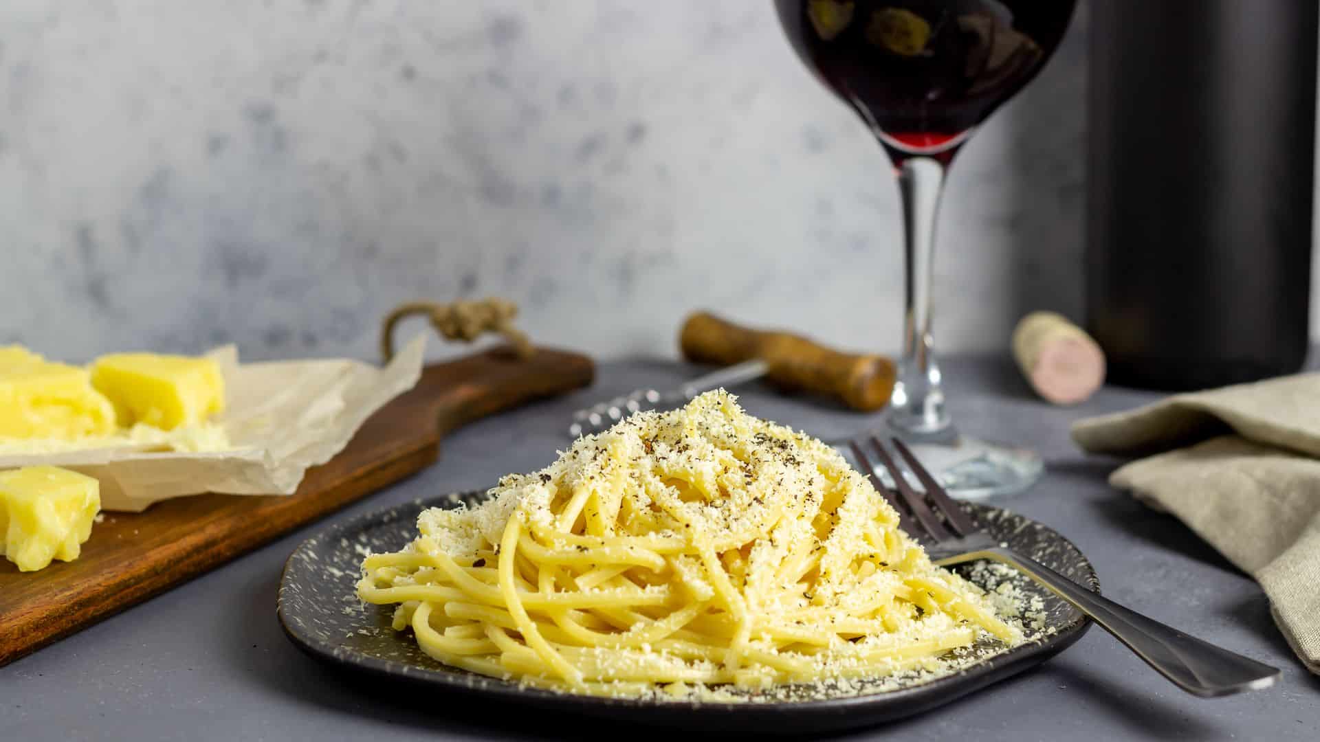 A plate of 'Cacio e Pepe', a Roman pasta dish and a glass of red wine.