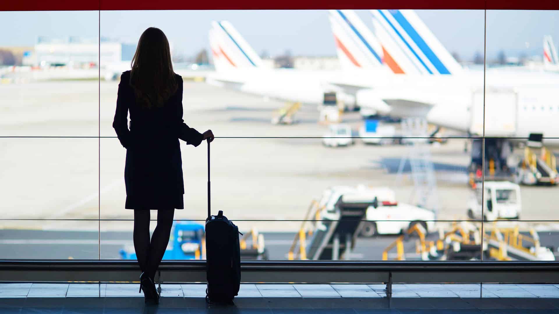 A woman watches the view of airplanes from inside the airport.