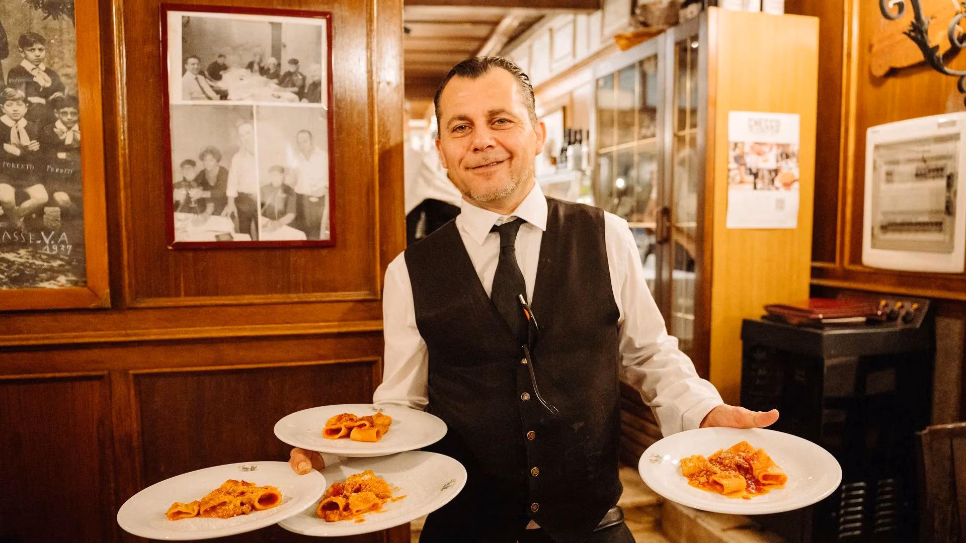Smiling waiter serving plates of traditional Roman pasta.